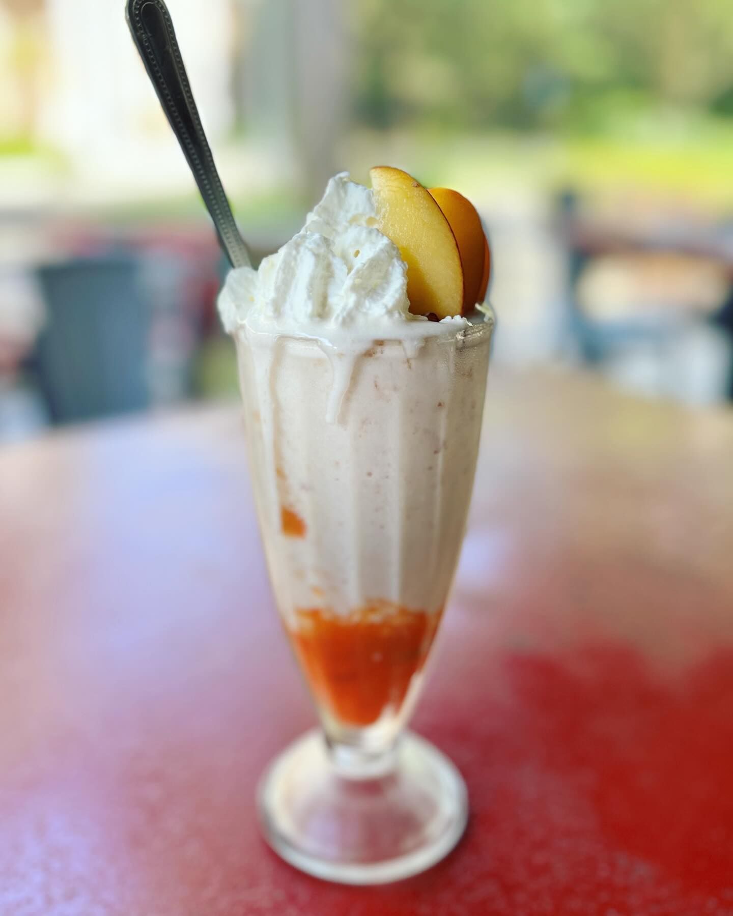 A milkshake with whipped cream and peaches on top