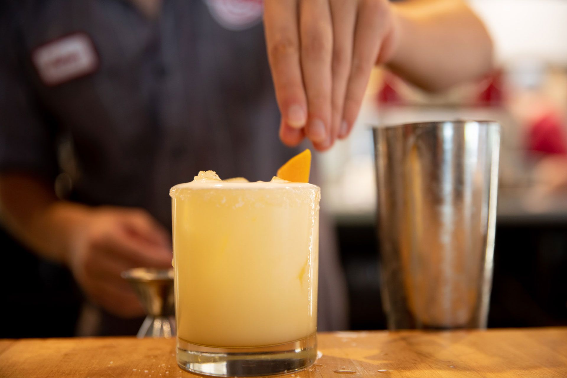 a bartender is adding a slice of orange to a margarita