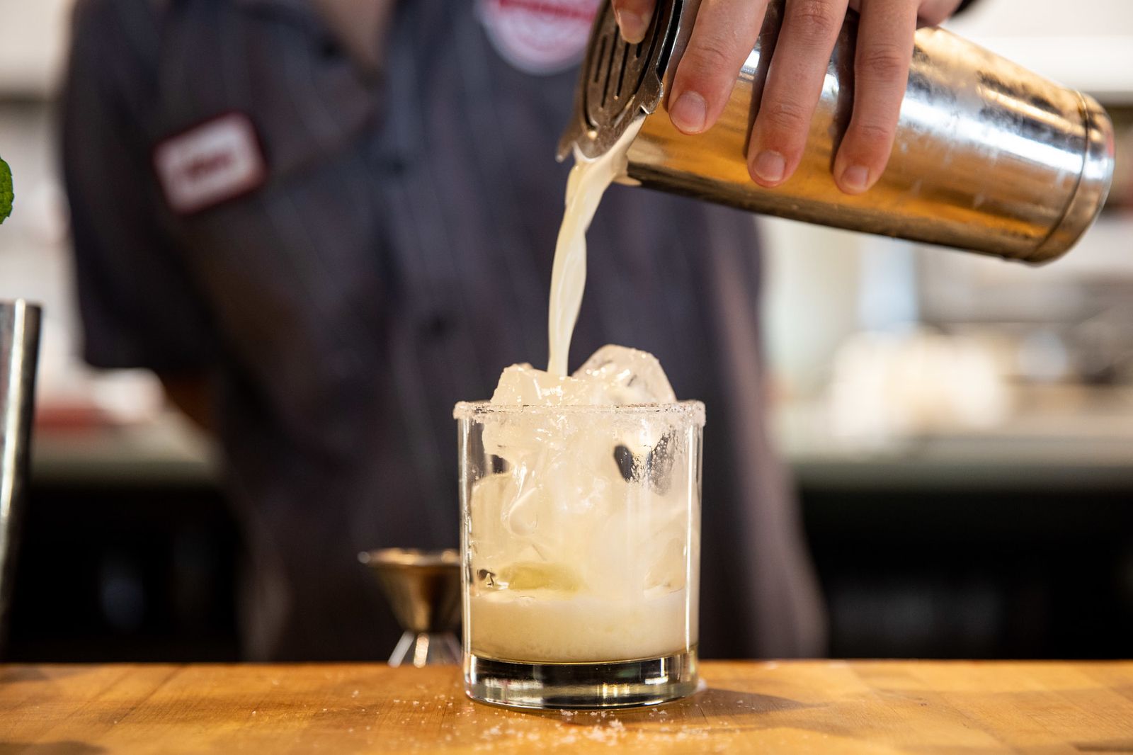 a bartender is pouring a drink into a glass with ice