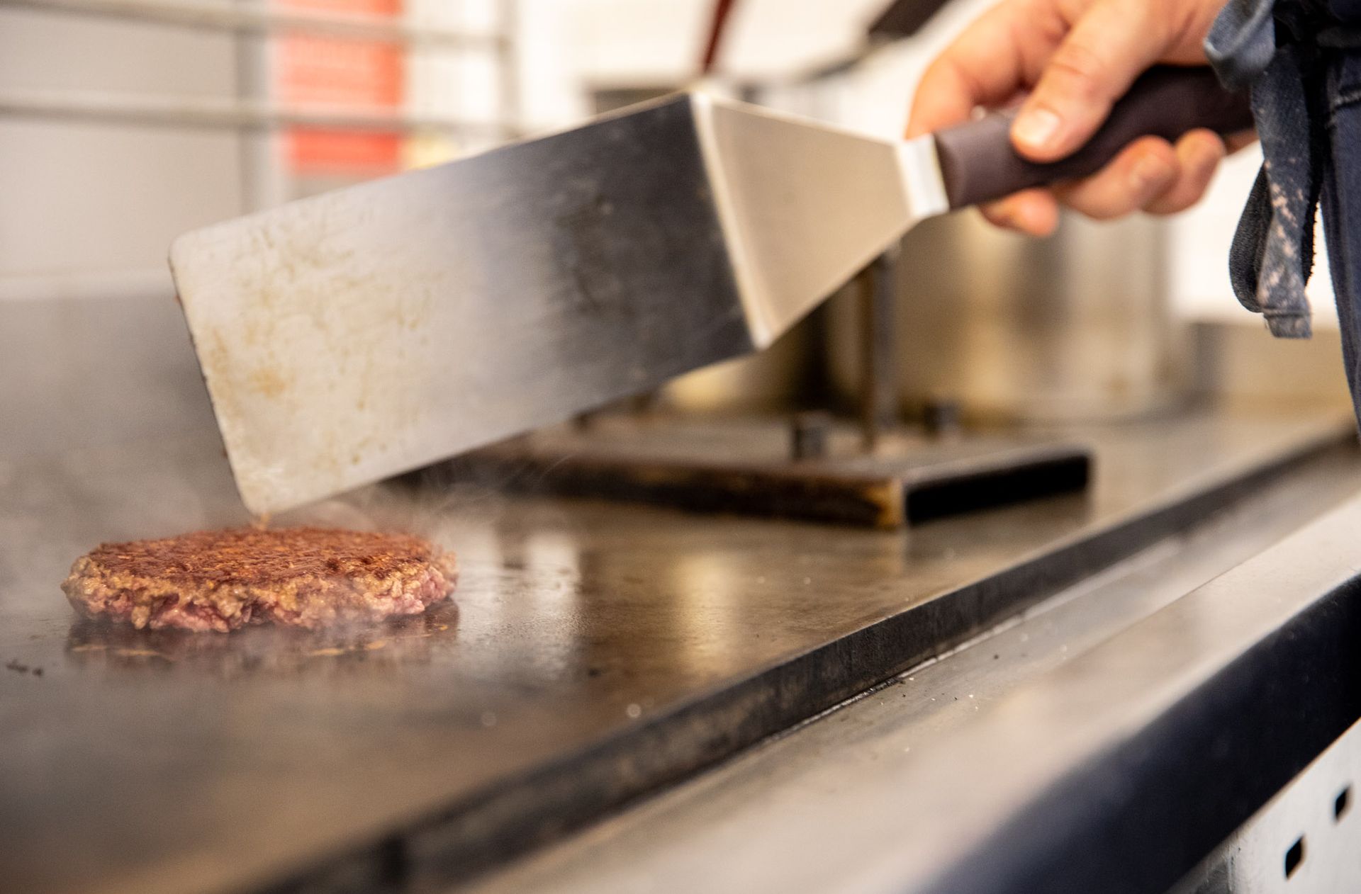a person is cooking a hamburger on a grill with a spatula