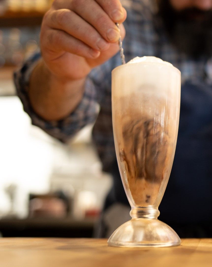 a man is stirring a milkshake with a spoon
