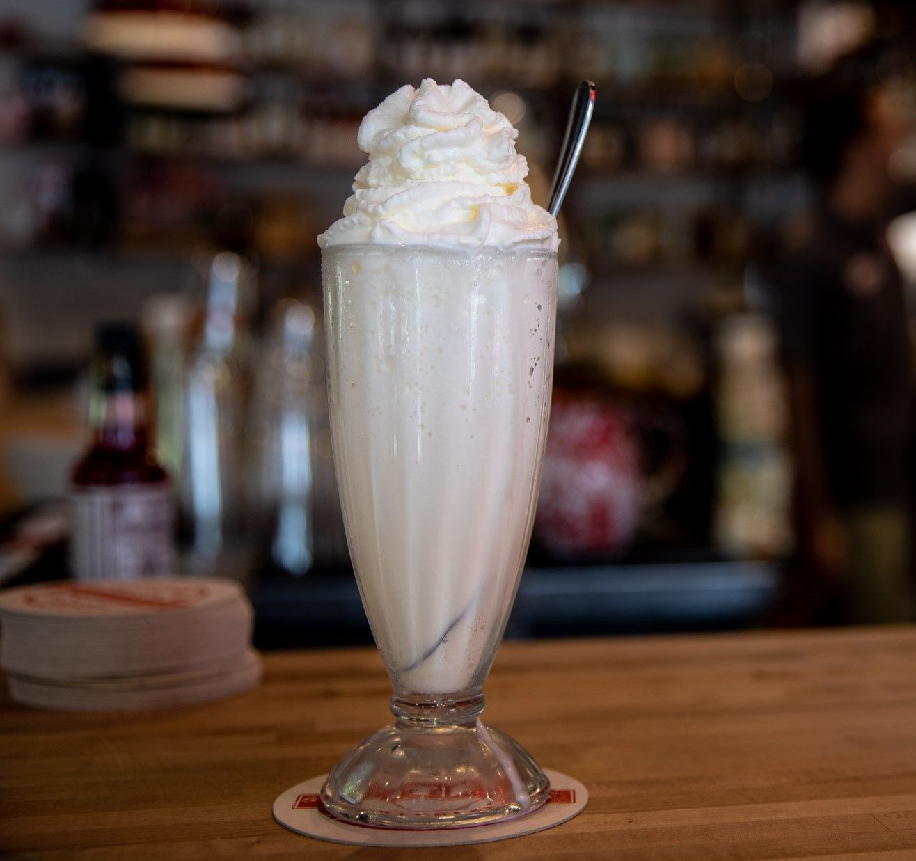 a milkshake with whipped cream and a spoon in it
