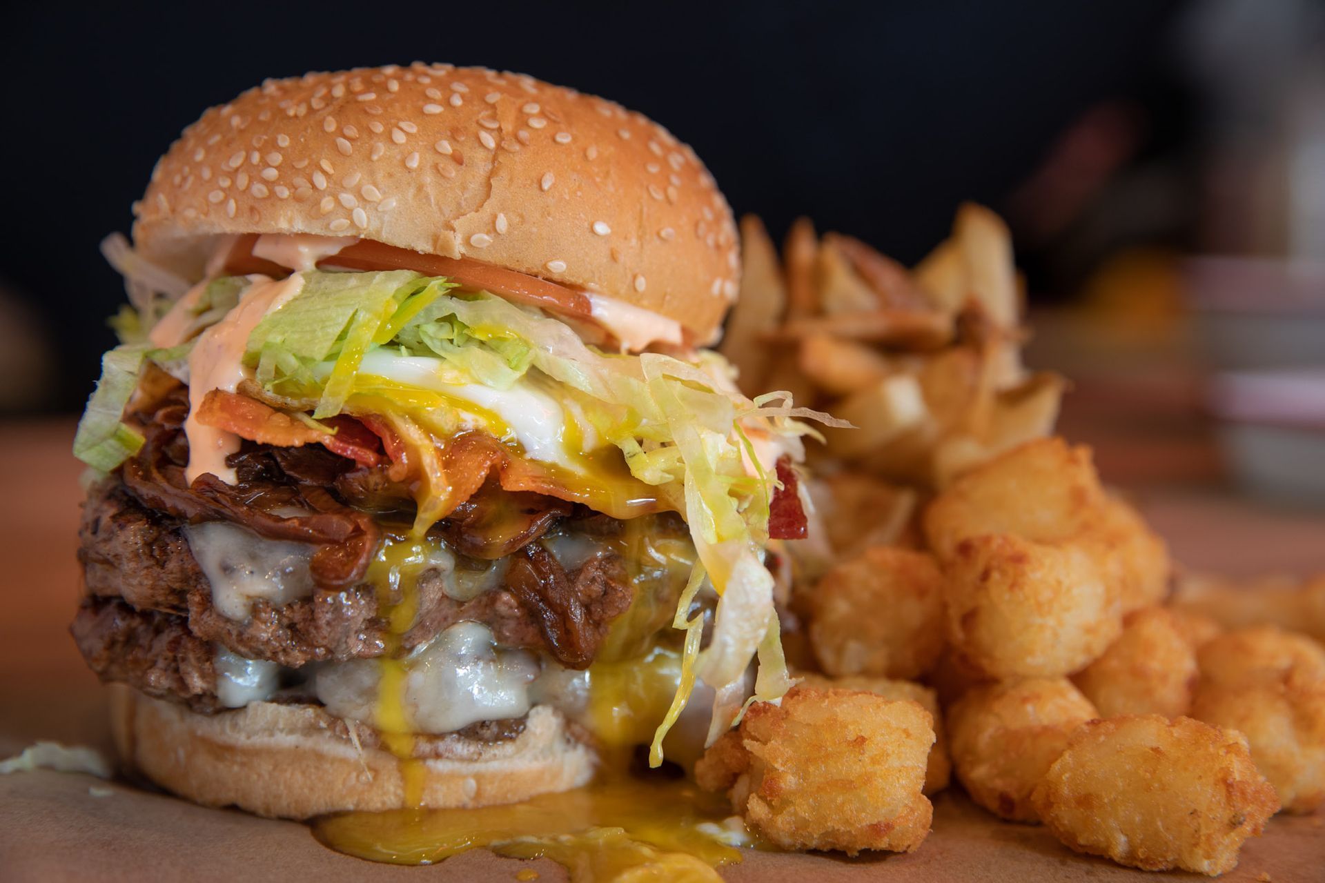a close up of a hamburger and fried potatoes on a table