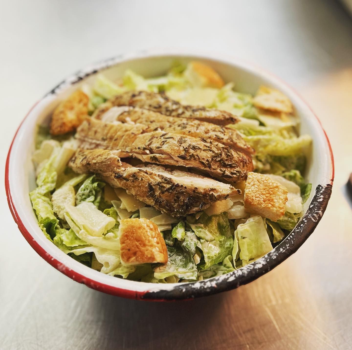 A bowl of salad with chicken and lettuce on a table