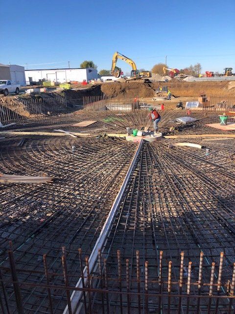 a man is working on a construction site with a yellow excavator in the background