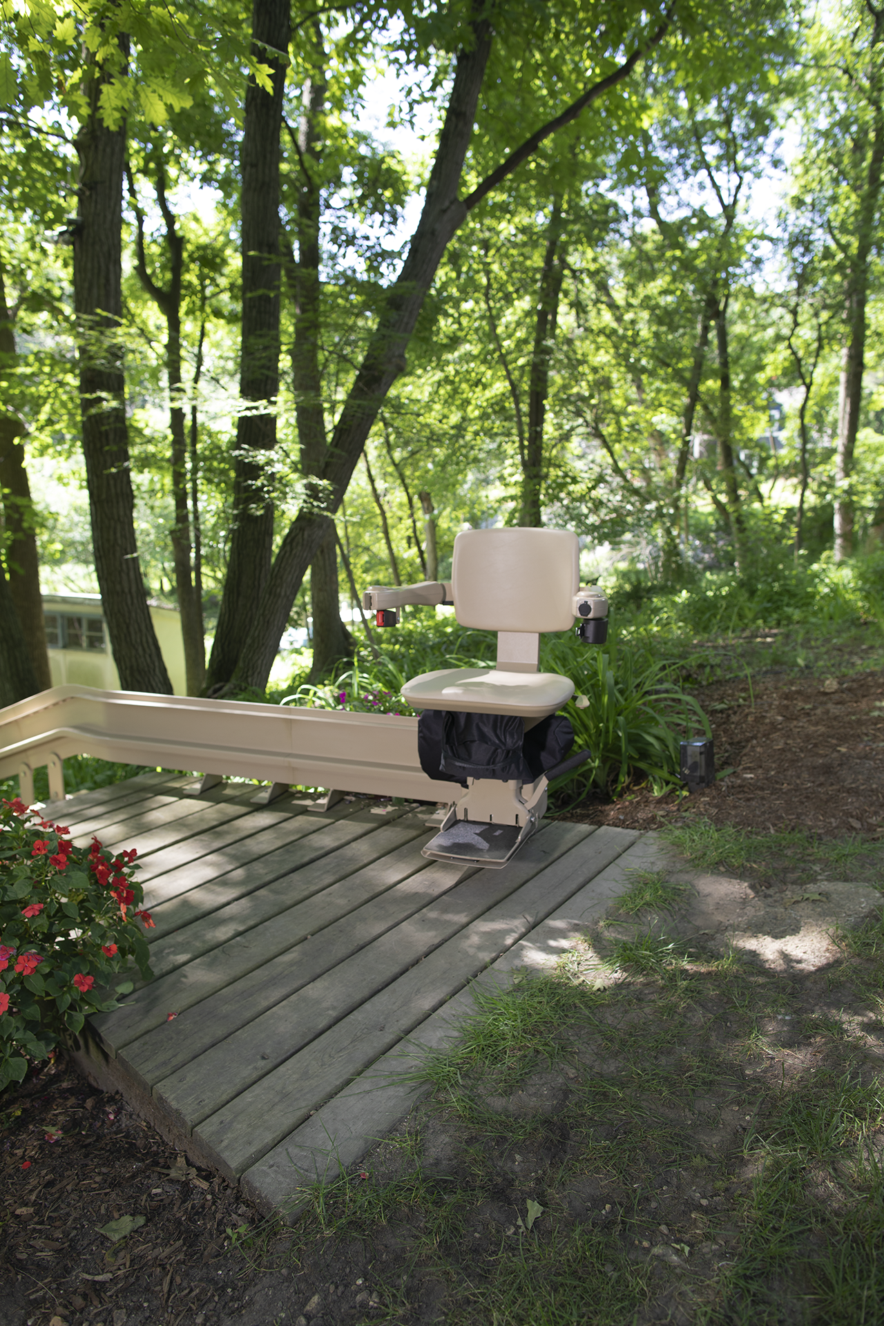 A wooden deck with a chair on it in the middle of a forest.