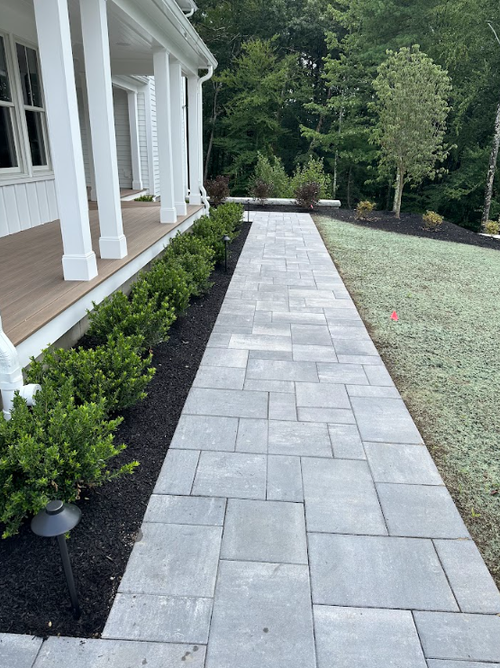 A stone walkway leading to a house with a hot tub in the backyard