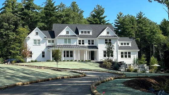 A man is working on a lawn in front of a blue house.