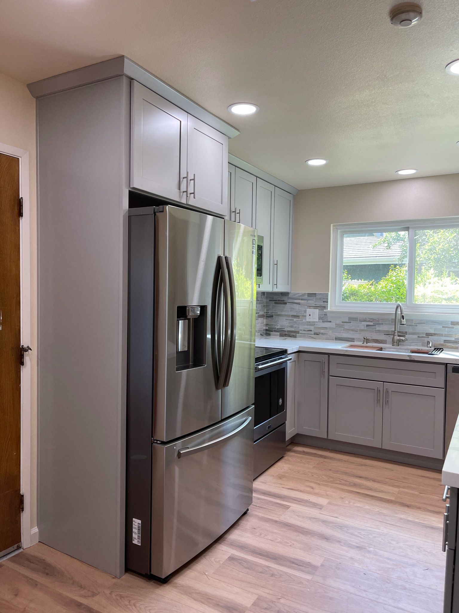 A kitchen with stainless steel appliances and wooden floors.