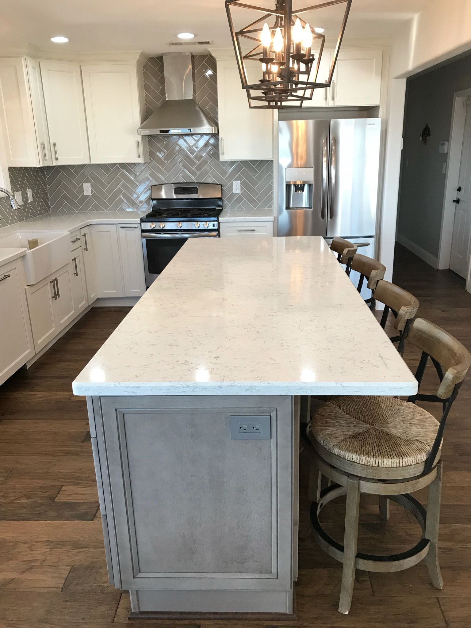 A kitchen with white cabinets , stainless steel appliances and a large island.