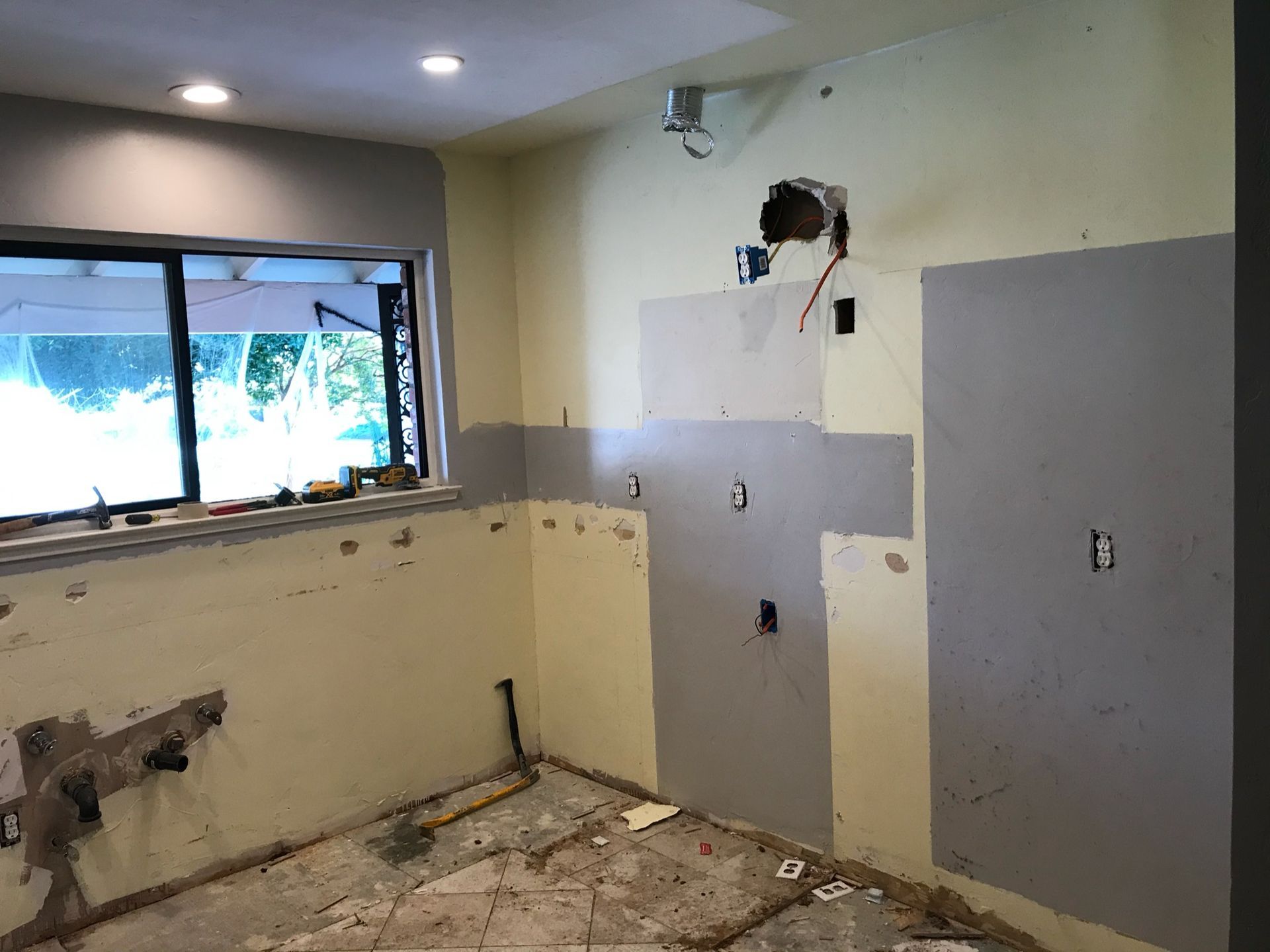 A kitchen under construction with a window and a hole in the wall.