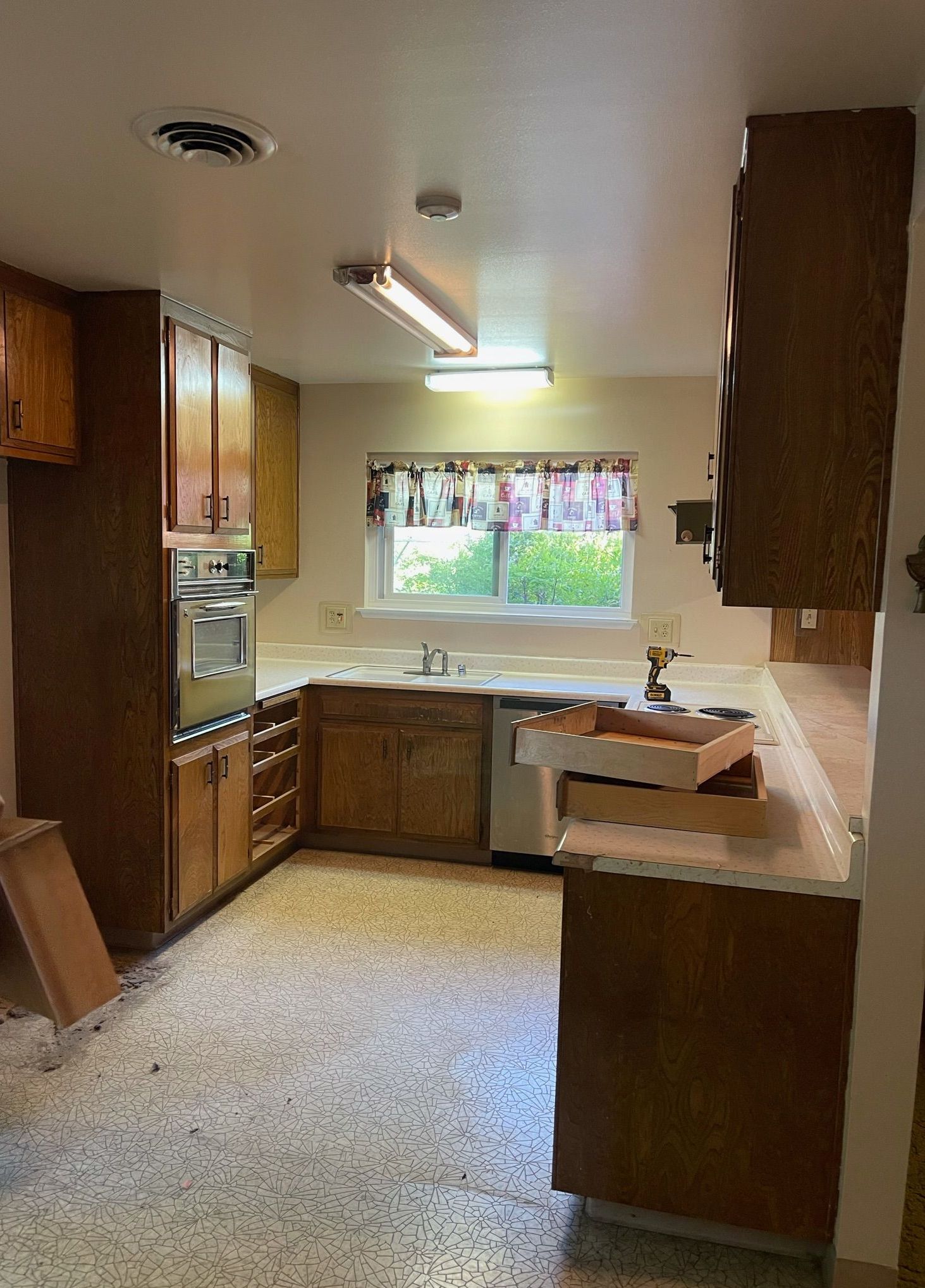 A kitchen with wooden cabinets , a sink , and a window.