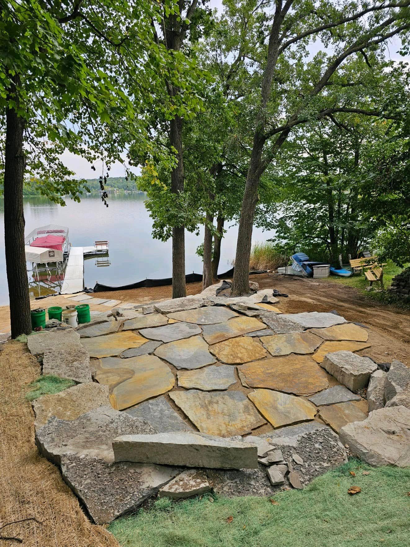 A large stone patio is being built next to a lake