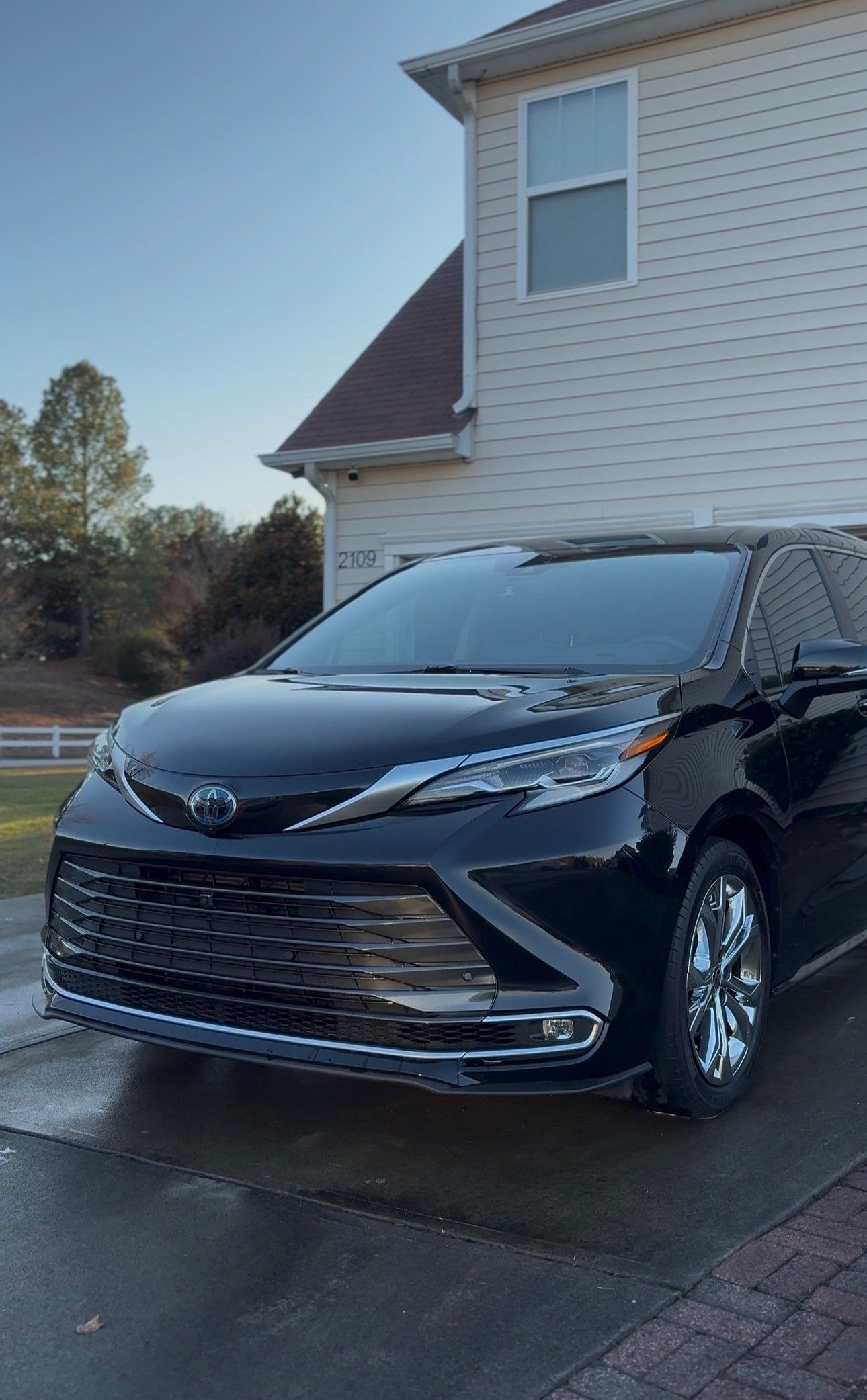 Black Toyota Sienna minivan parked in front of a house on a sunny day.