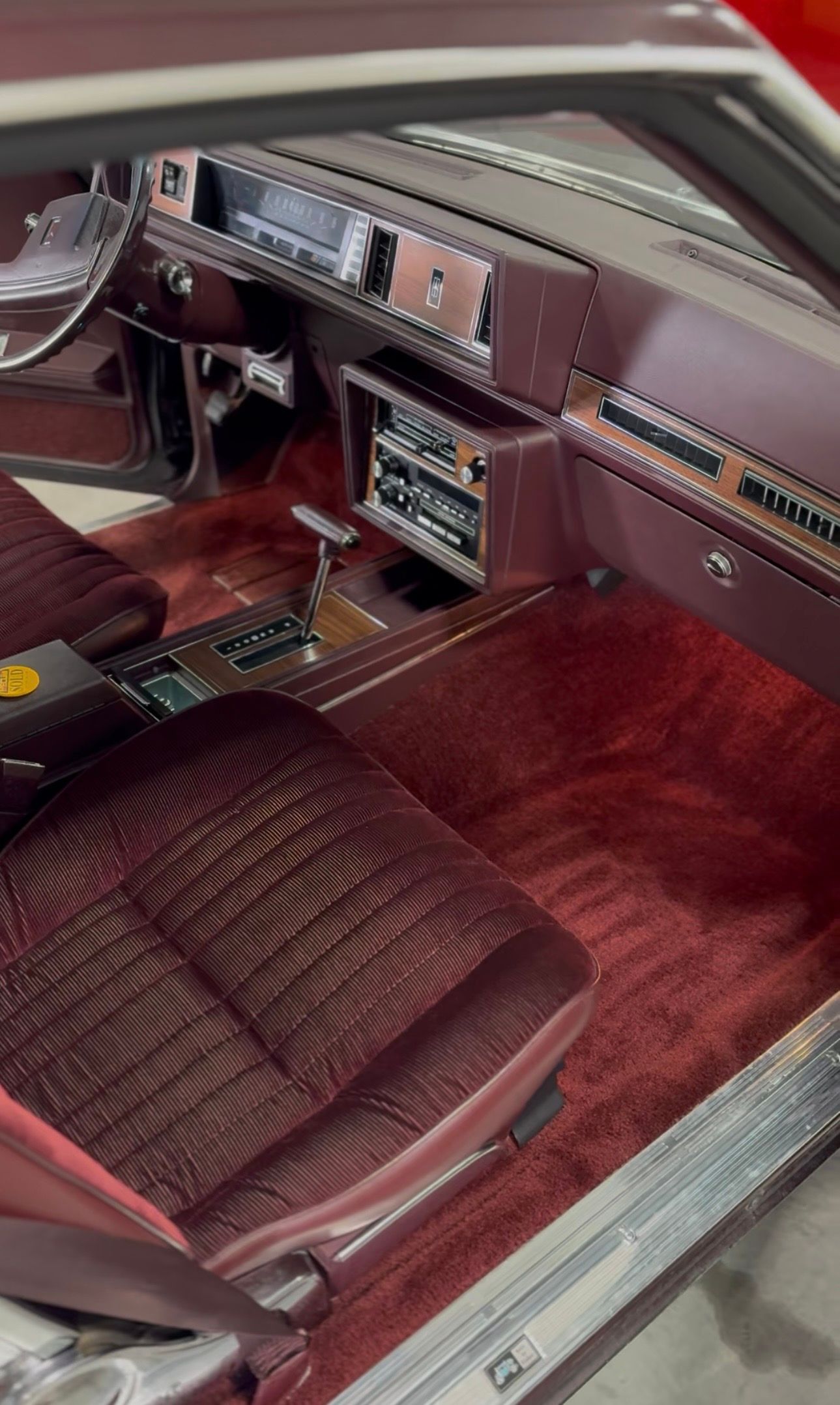 Maroon interior of a classic car: seats, carpet, dashboard, and radio.