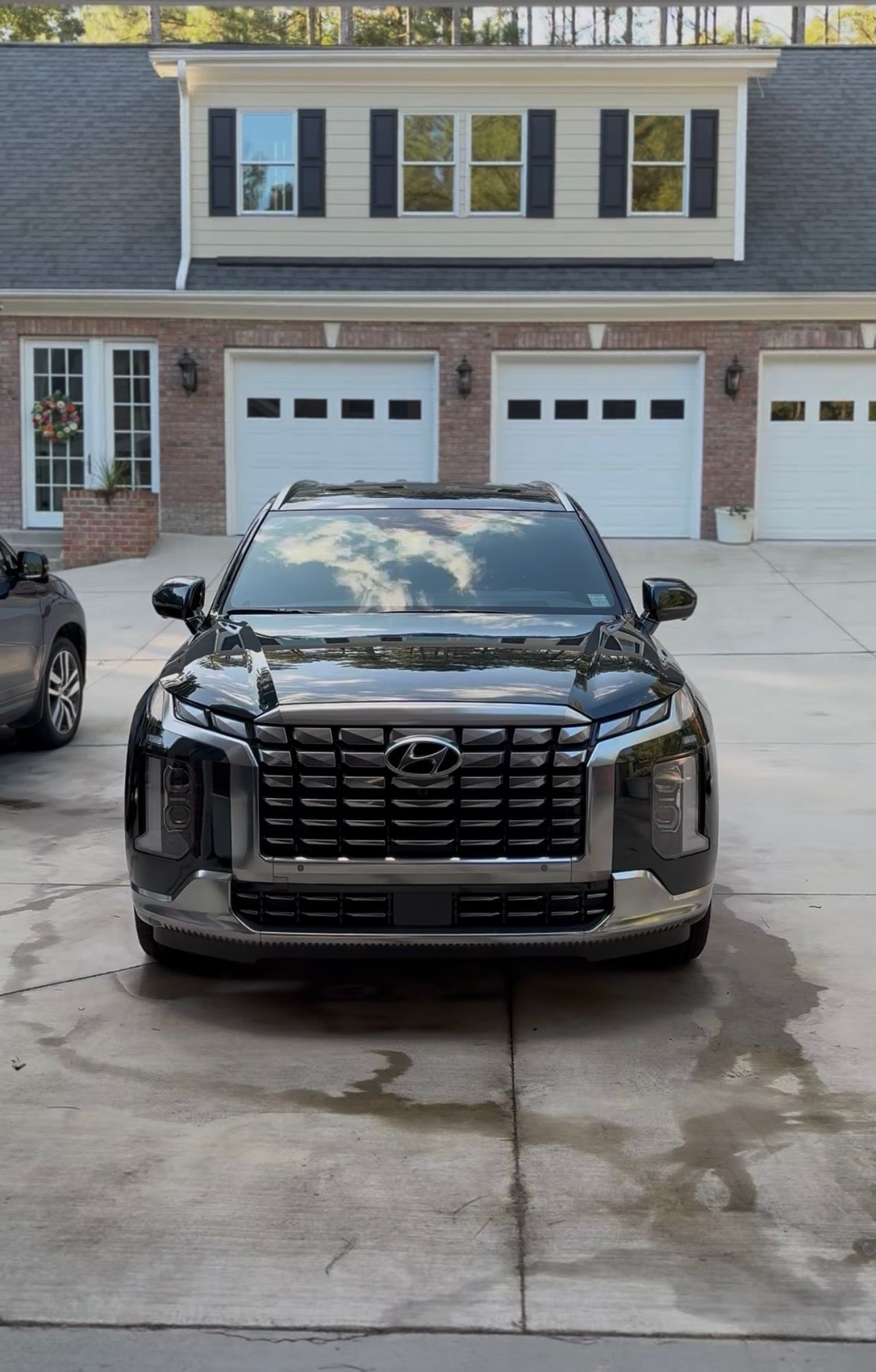 Black Hyundai SUV parked in front of a house with white garage doors.