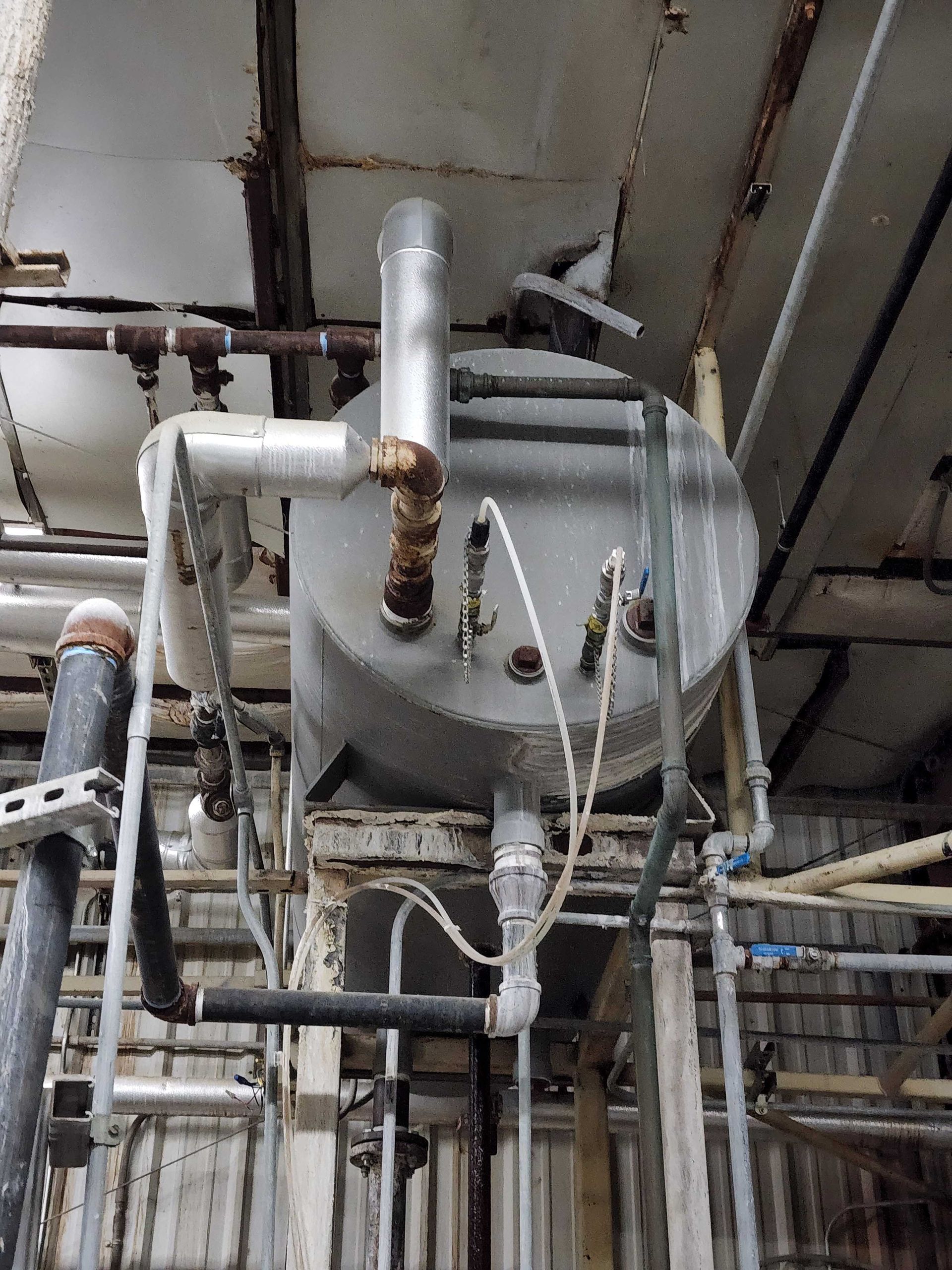 Large metal tank with pipes and valves in an industrial setting, possibly for processing liquids.