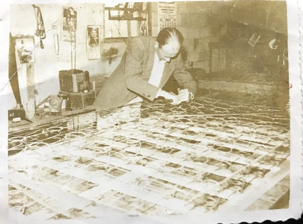 A black and white photo of a man working on a piece of paper