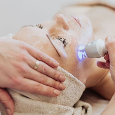 A woman is getting a facial treatment with a light on her face