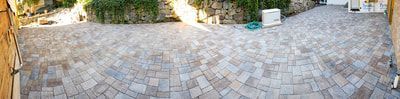 A wide-angle view of a patio paved with rectangular stone tiles in shades of gray, brown, and tan.