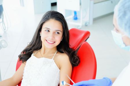 A little girl is sitting in a dental chair and smiling.