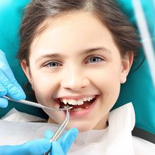 A little girl is getting her teeth examined by a dentist