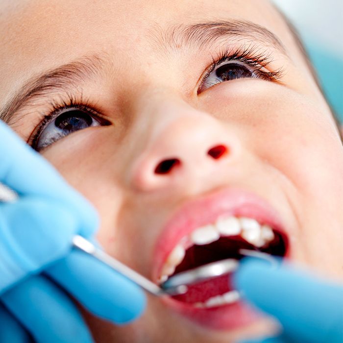A young boy is getting her teeth examined by a dentist