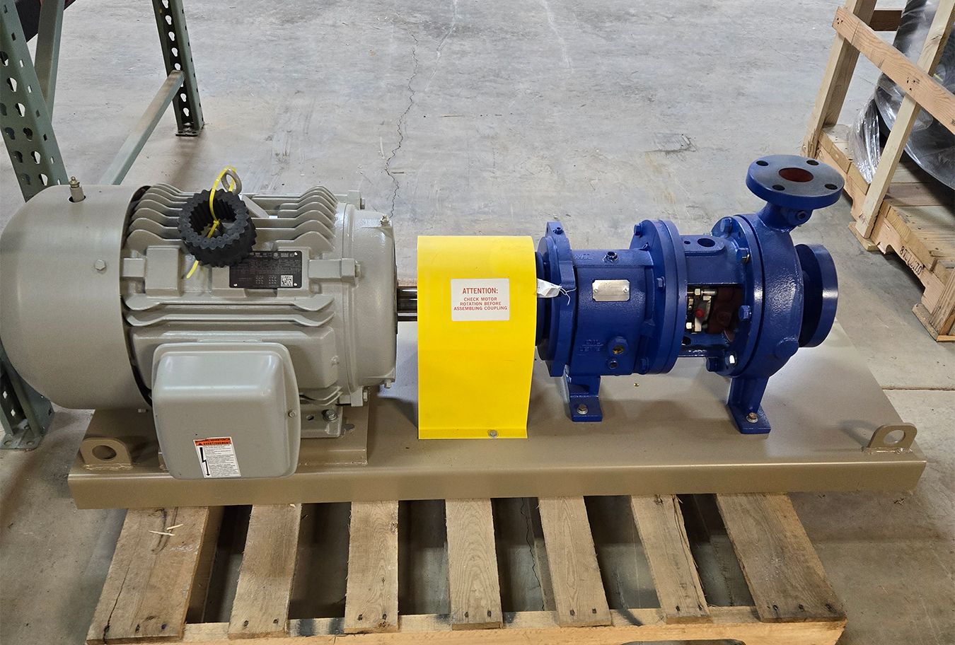 A pump with a motor attached to it is sitting on a wooden pallet