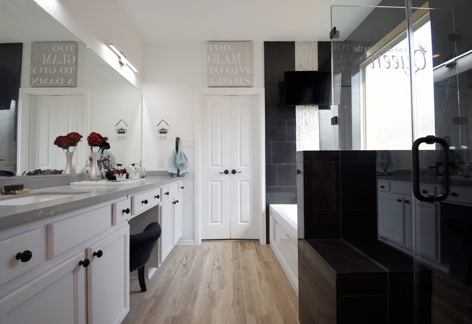 Modern white bathroom with dark accents: double vanity, shower, and door.
