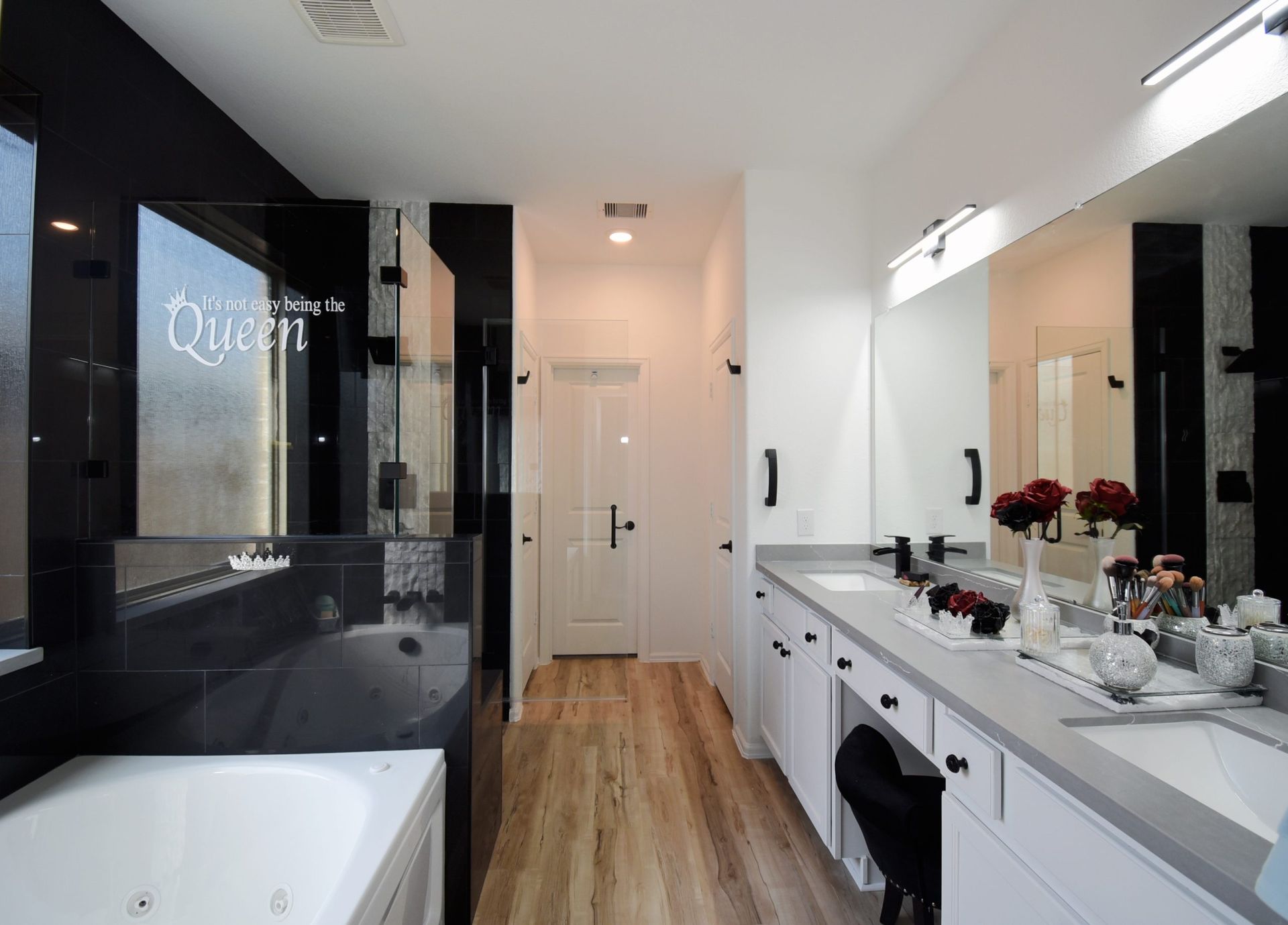 A luxurious bathroom with a white vanity, black accents, and a jacuzzi tub.