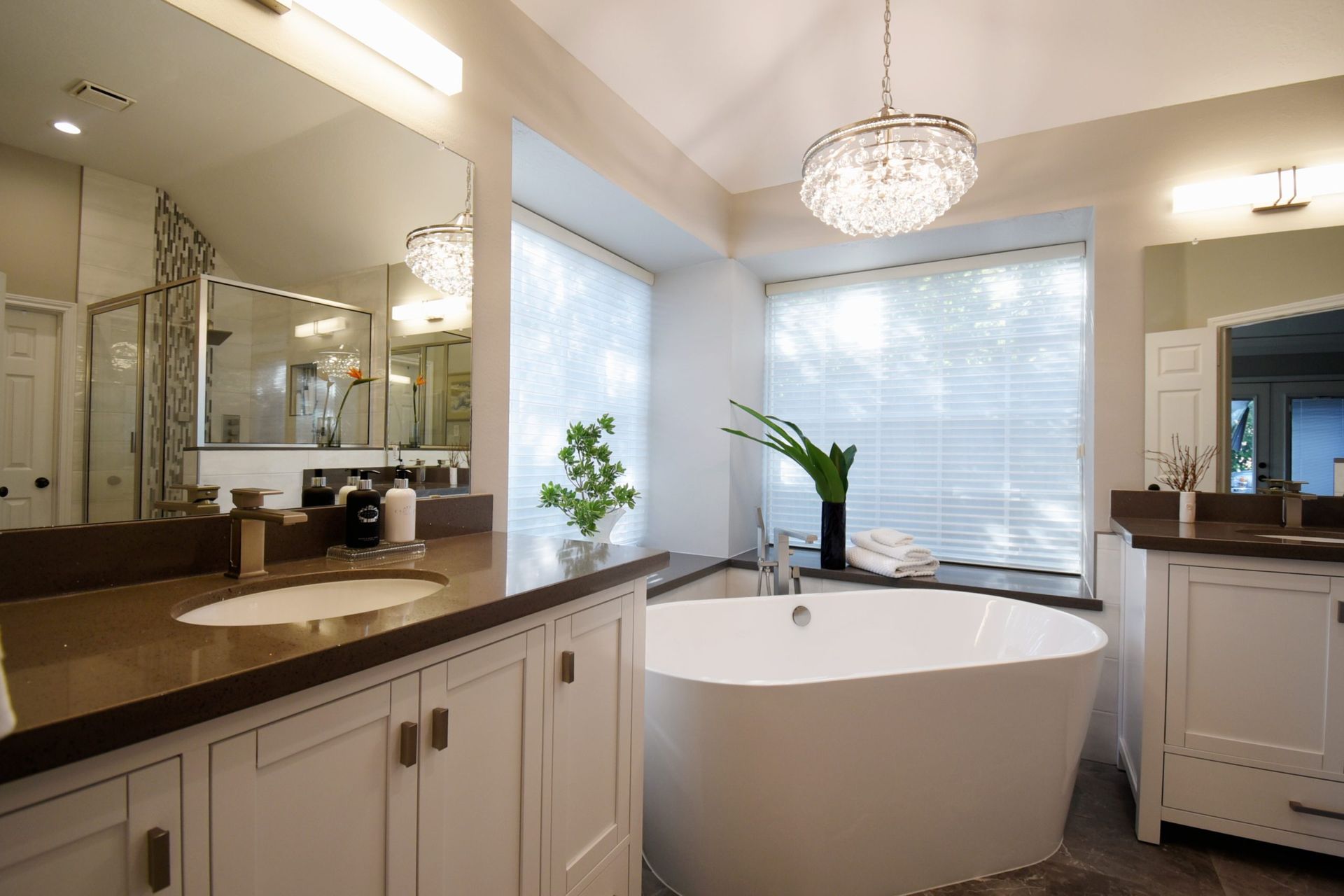 Bathroom with white cabinets, a freestanding tub, and a chandelier.