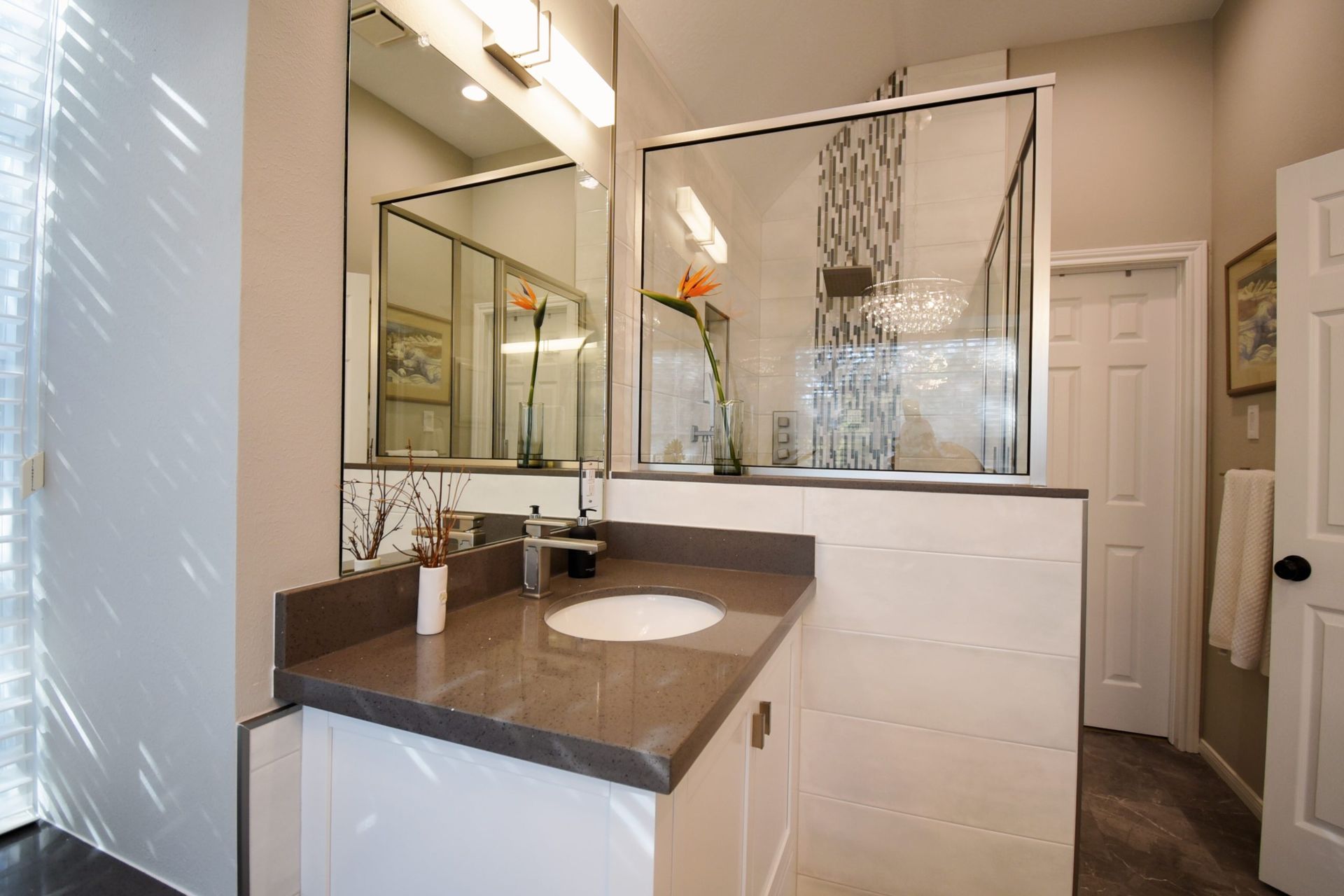 Bathroom with a white vanity, gray countertop, glass shower, and a large mirror.