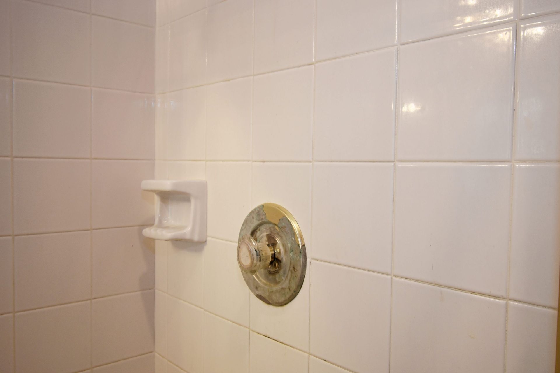 White tiled shower interior with soap dish and faucet.