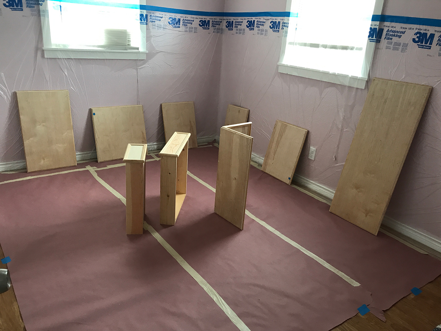Room under renovation with wood panels propped against pink insulation.