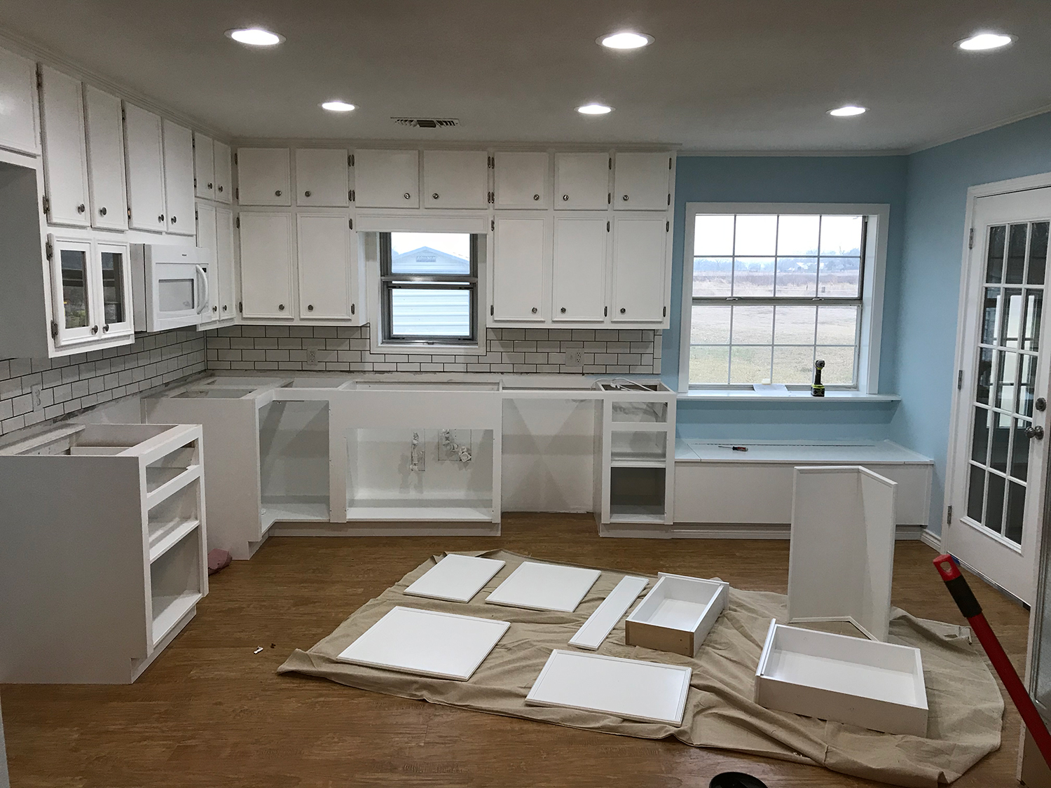 Kitchen renovation with white cabinets, blue walls, and wood flooring.