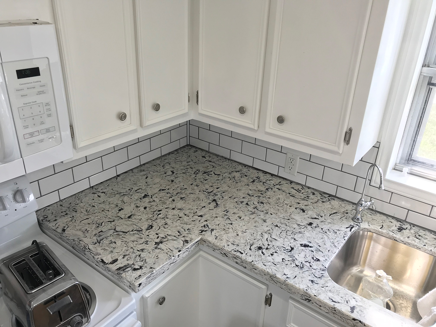 White kitchen with granite countertops and subway tile backsplash.