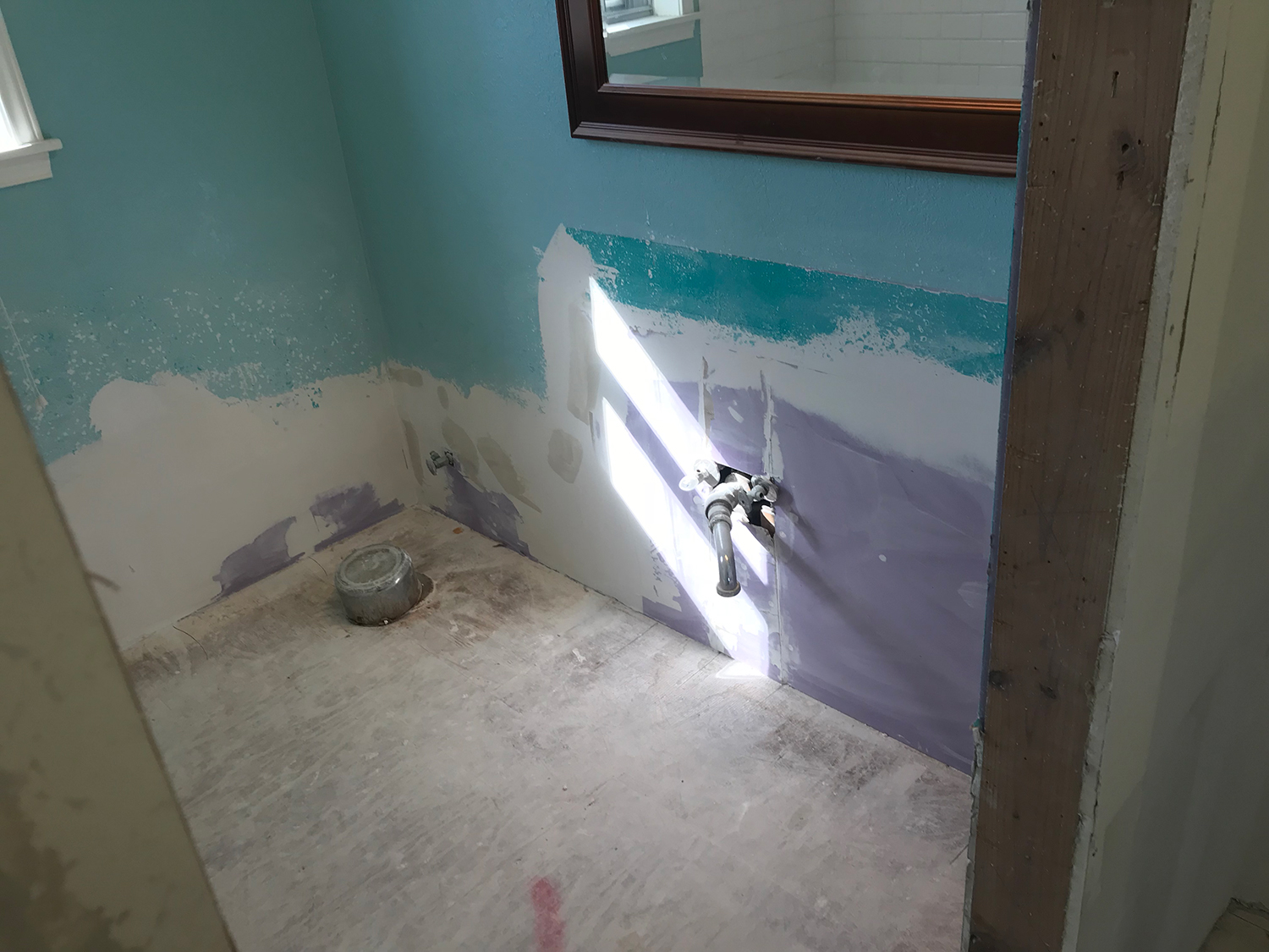 Bathroom under renovation, blue and purple walls, exposed plumbing, concrete floor.