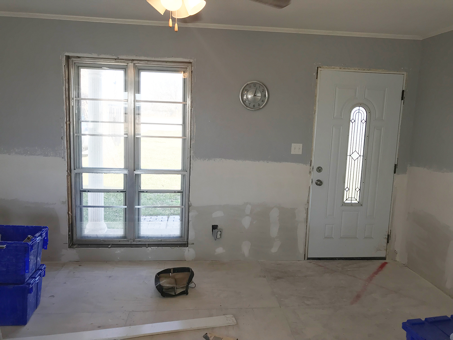 Room interior with unfinished drywall, gray walls, a door, and a window.