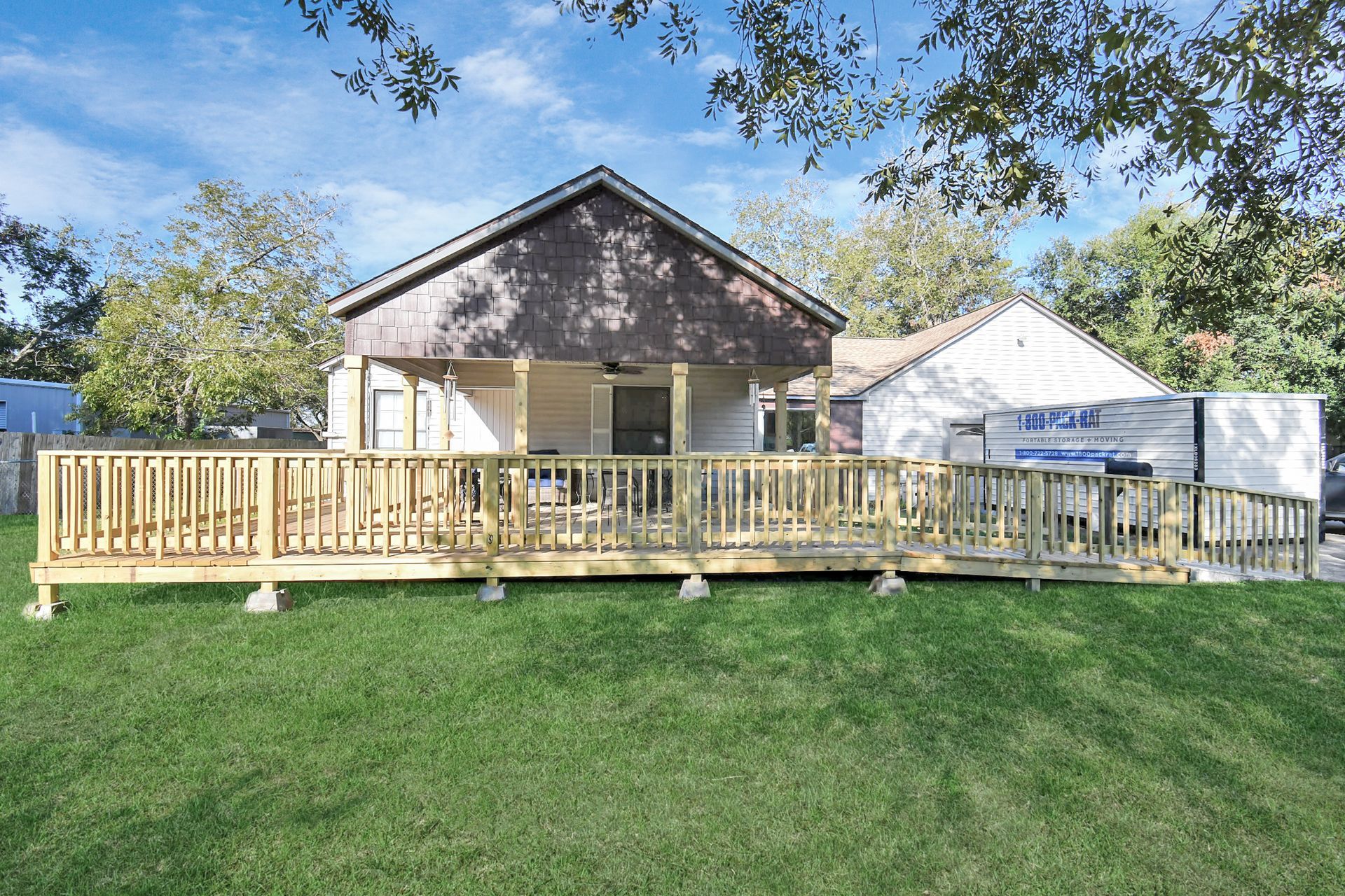 Wooden deck with ramp attached to a house, on a grassy lawn.