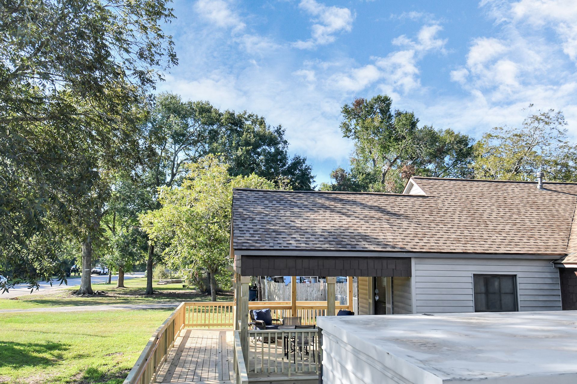 Wooden deck with ramp attached to a house overlooking a grassy area with trees and a cloudy sky.