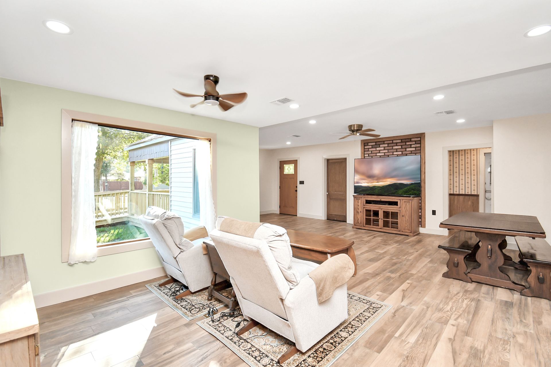 Living room with two recliner chairs, TV, wood floors, and window.