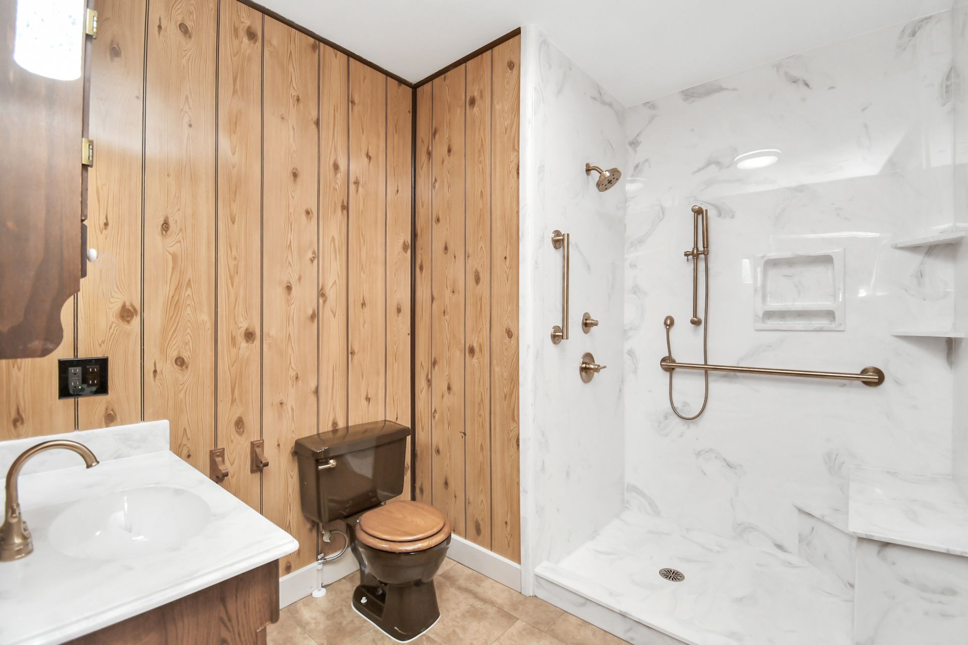 Bathroom with wood-paneled walls, dark toilet, and accessible white shower with grab bars and marble design.