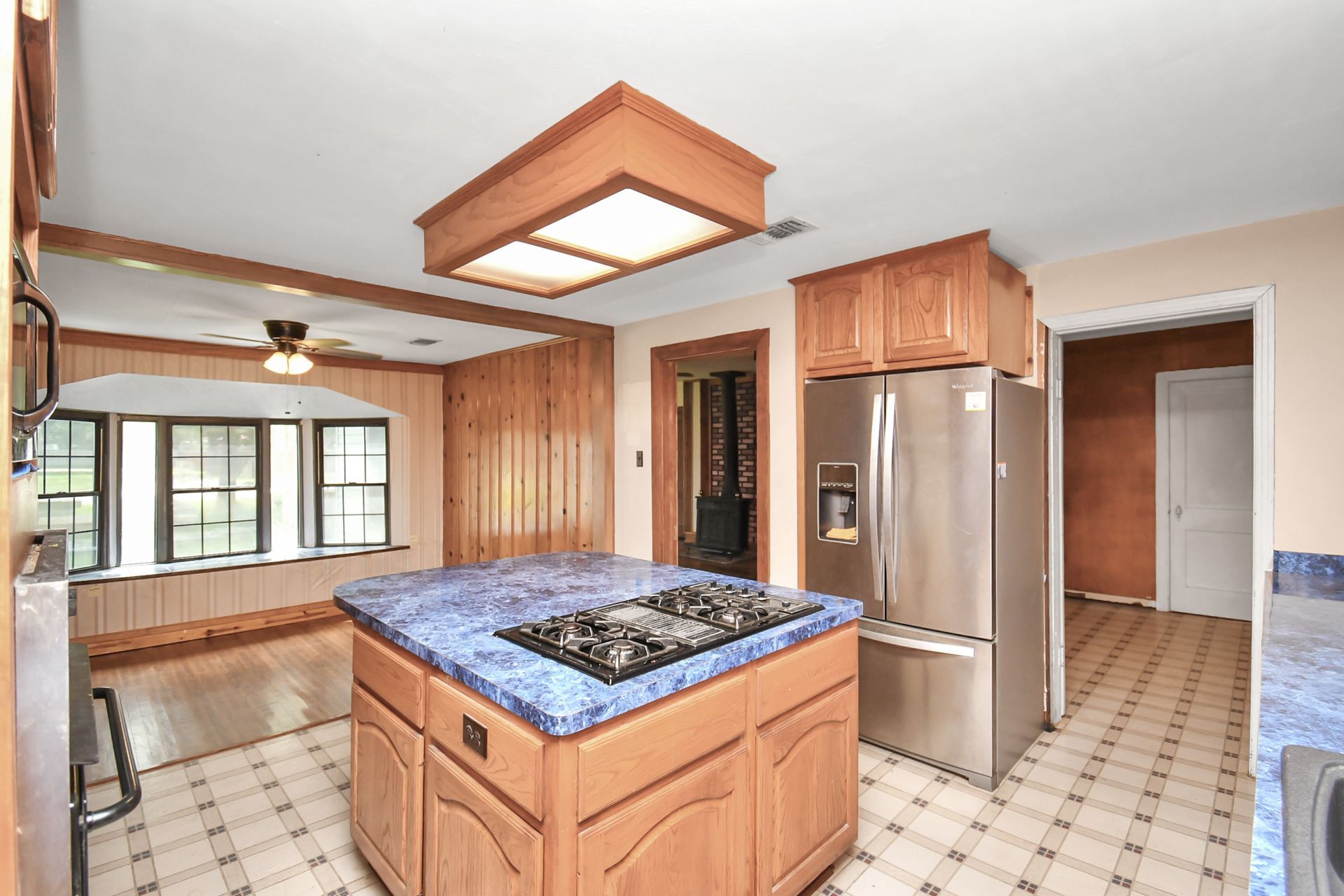 Kitchen with wood cabinets, stainless steel appliances, blue countertop, and tile floor.