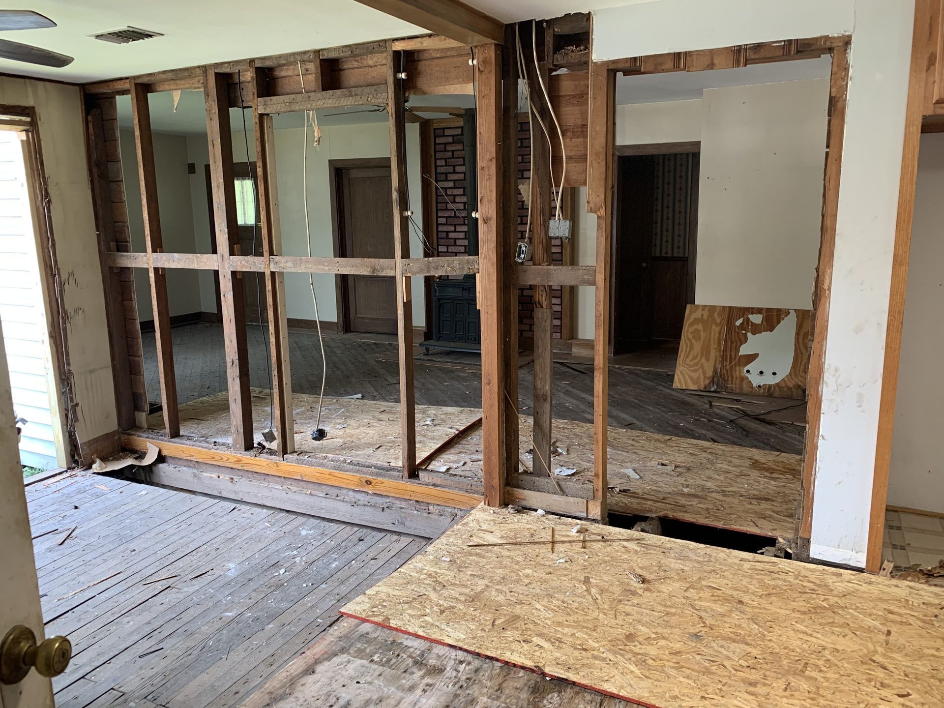 Interior view of a room undergoing renovation. Exposed wooden framing, missing walls/flooring.