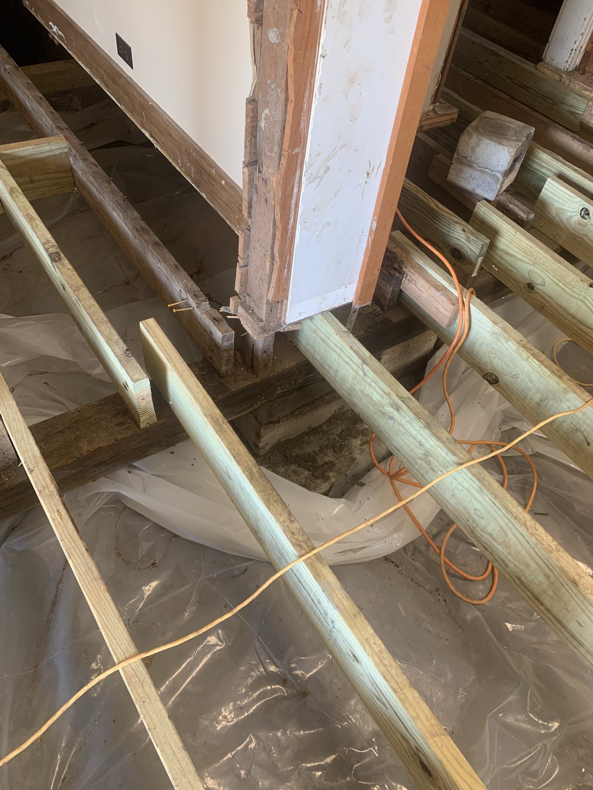 View of exposed wooden floor joists, construction in progress; a column base visible.