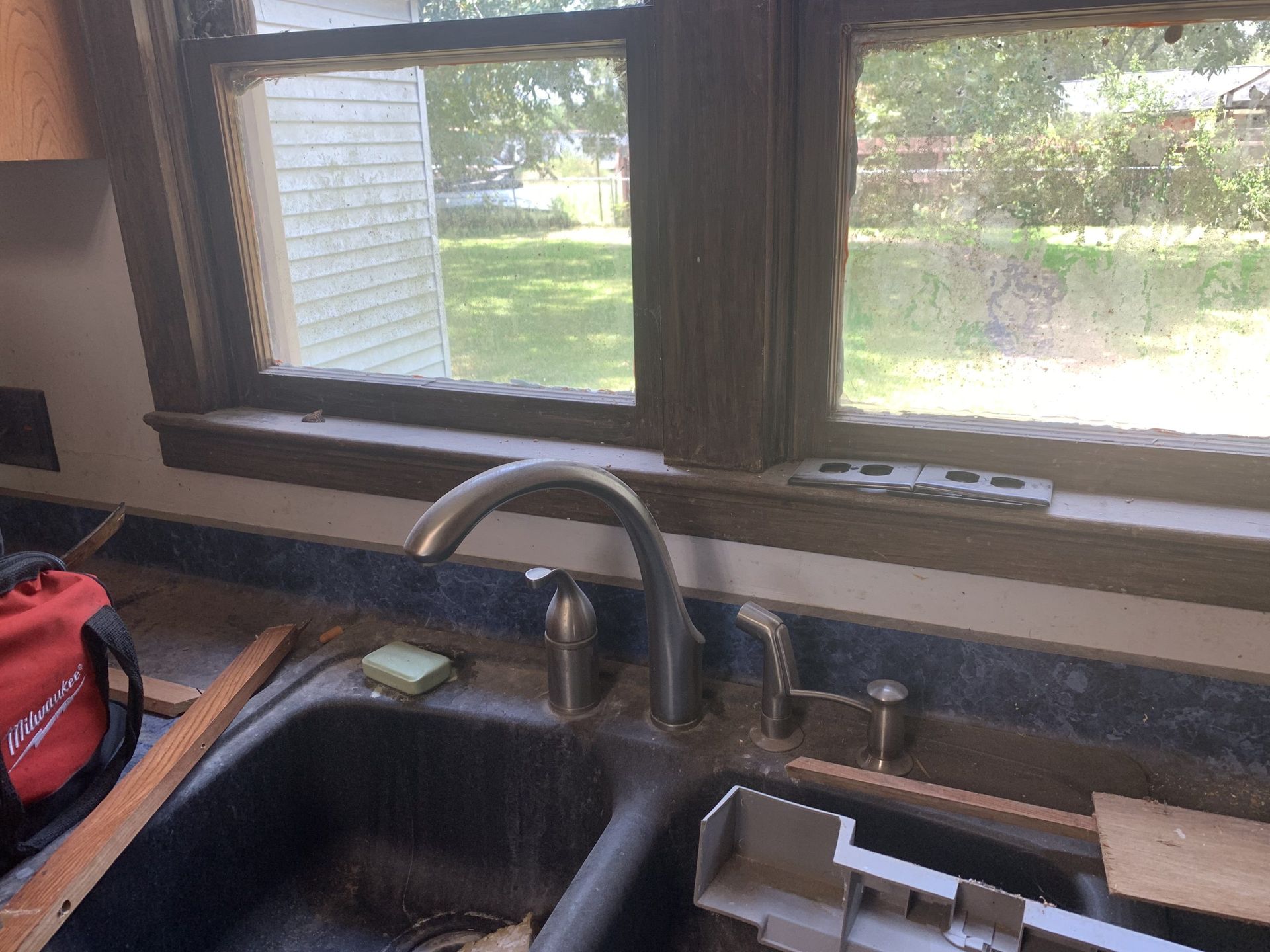Kitchen sink with faucet under a window, a level sits on the sill.