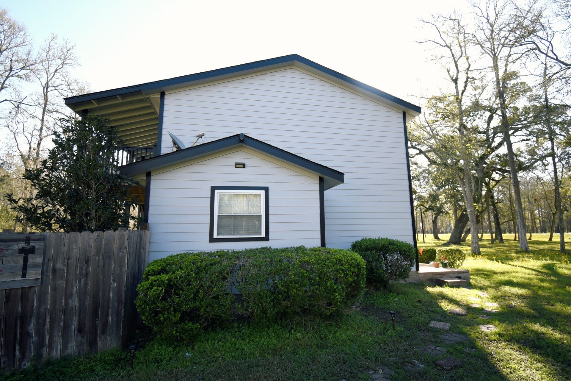 Side view of a two-story building with light blue siding, a small outbuilding, and a grassy yard.