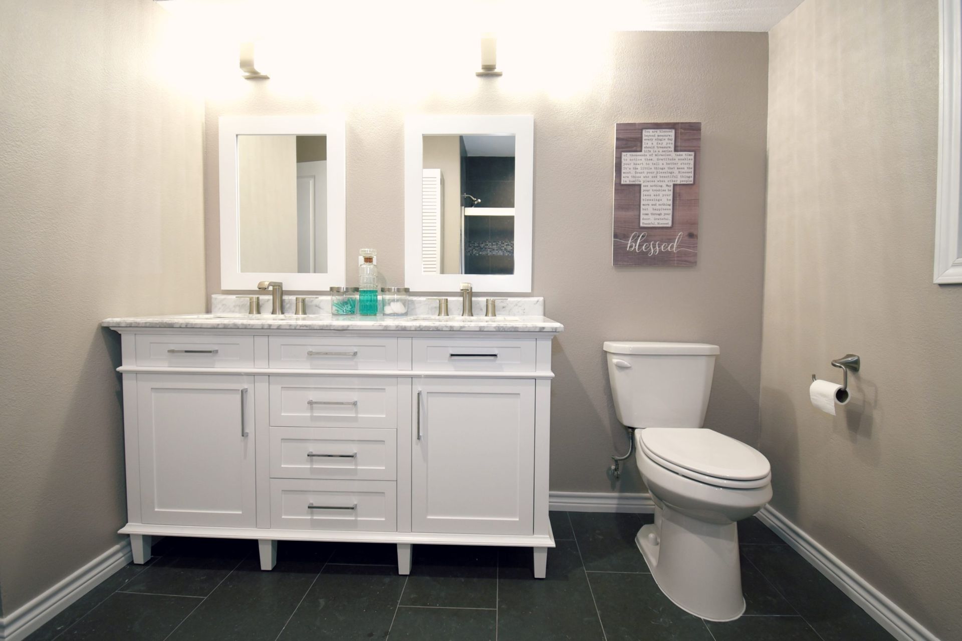 White double vanity in a bathroom with a toilet and decorative cross.