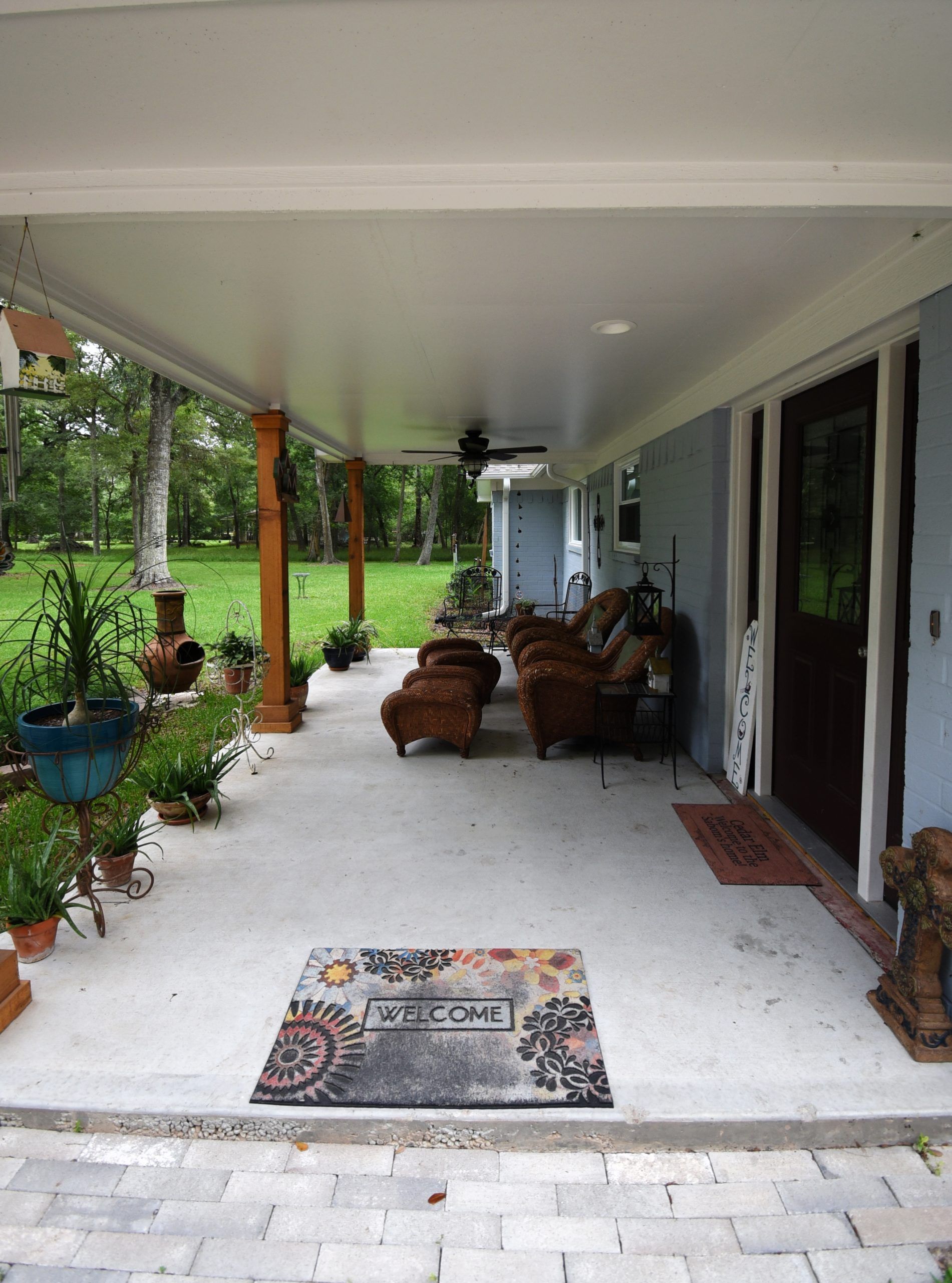 Covered porch with furniture, potted plants, and a 