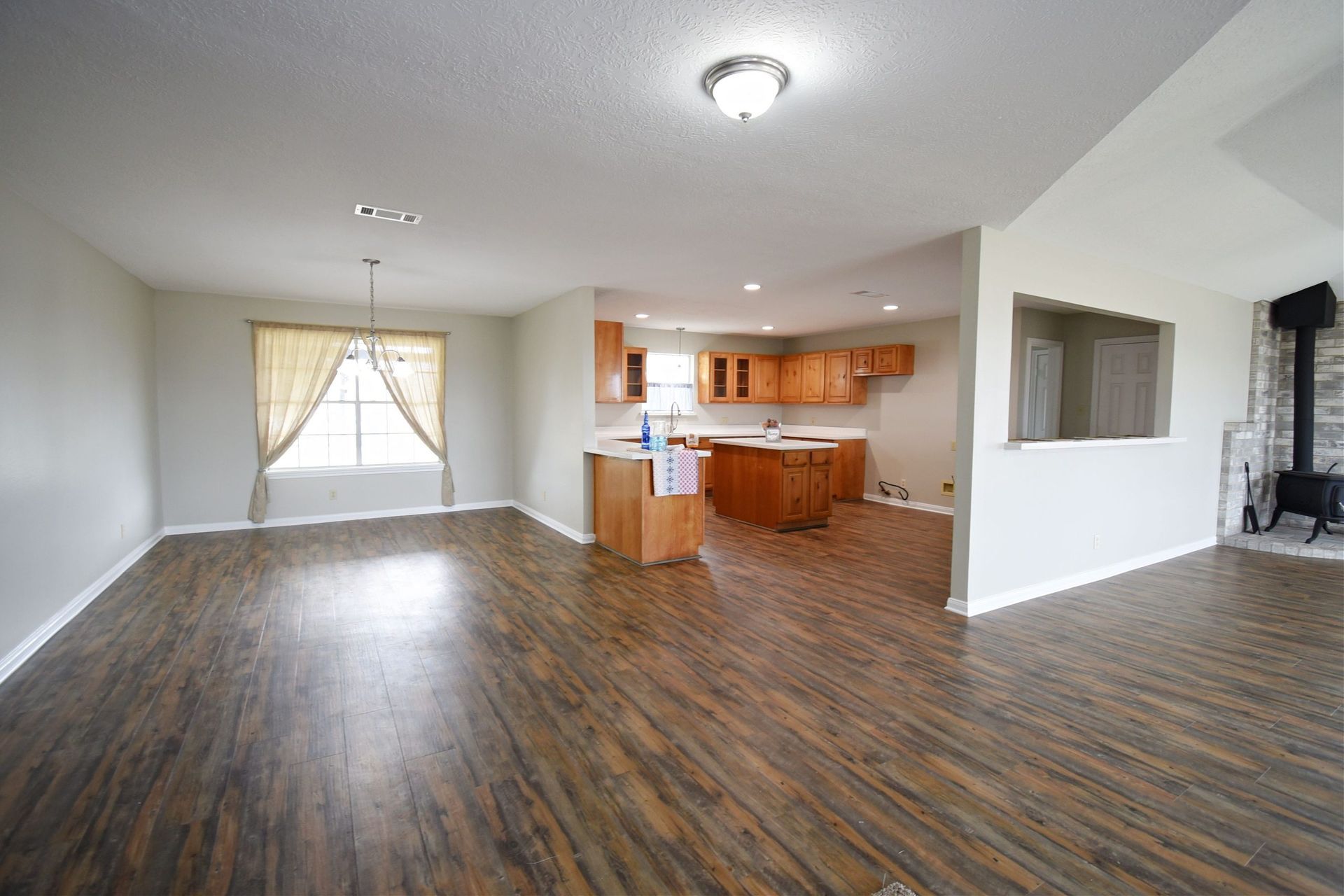 Open-concept living space with wood floors, kitchen, and fireplace.
